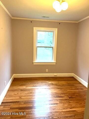 empty room with ornamental molding and hardwood / wood-style flooring