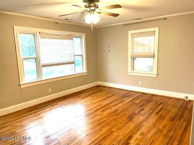 spare room with wood-type flooring, crown molding, and a healthy amount of sunlight