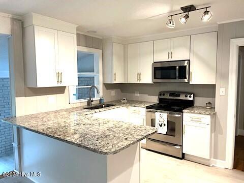 kitchen featuring sink, appliances with stainless steel finishes, white cabinetry, light stone counters, and kitchen peninsula