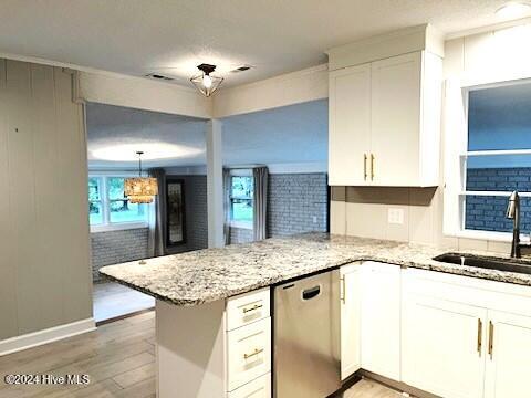 kitchen featuring dishwasher, sink, kitchen peninsula, hardwood / wood-style floors, and white cabinets