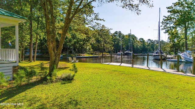 surrounding community featuring a boat dock, a water view, and a yard