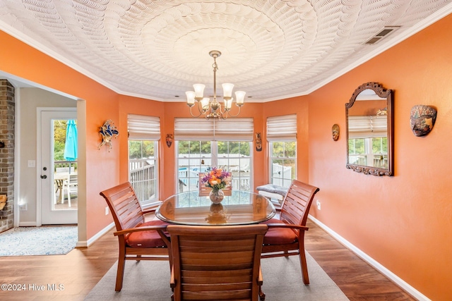 dining space featuring wood-type flooring, a notable chandelier, and ornamental molding