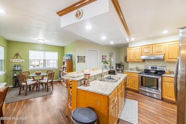 kitchen featuring a breakfast bar, stainless steel appliances, a kitchen island with sink, sink, and hardwood / wood-style flooring