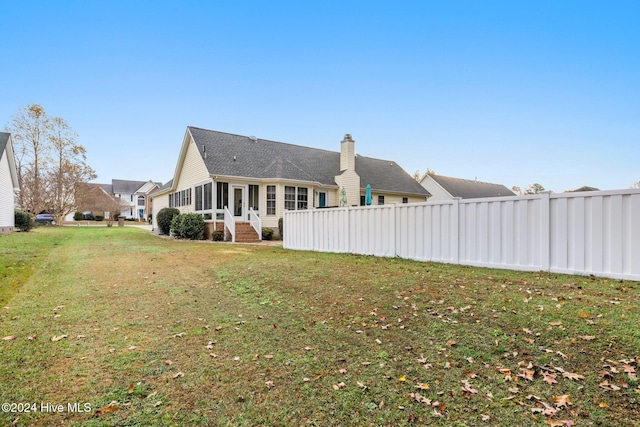 back of property with a lawn and a sunroom