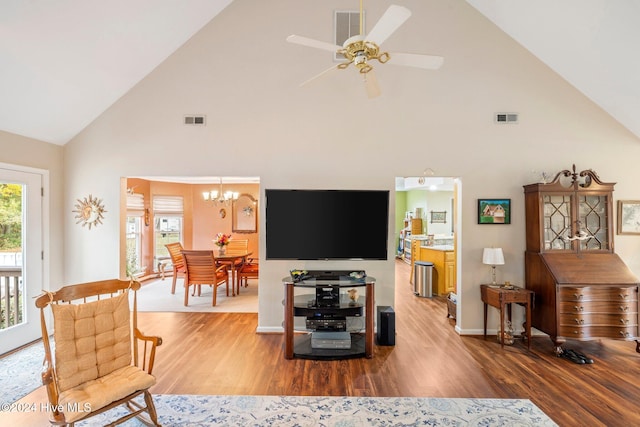 living room featuring ceiling fan with notable chandelier, hardwood / wood-style flooring, and high vaulted ceiling