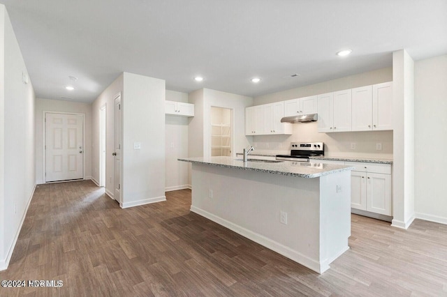 kitchen featuring electric stove, white cabinetry, and a center island with sink