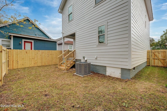 rear view of house with a lawn and cooling unit