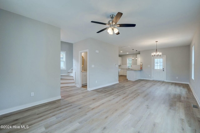 unfurnished living room with sink, ceiling fan with notable chandelier, and light wood-type flooring