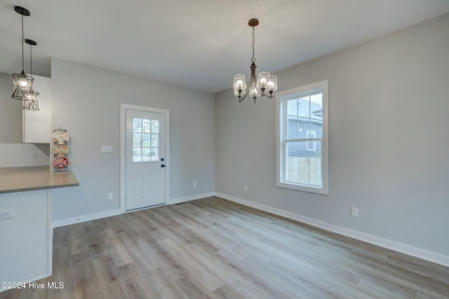 unfurnished dining area with light hardwood / wood-style floors and an inviting chandelier