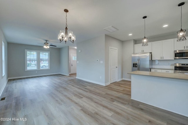 kitchen featuring appliances with stainless steel finishes, tasteful backsplash, ceiling fan with notable chandelier, decorative light fixtures, and white cabinets