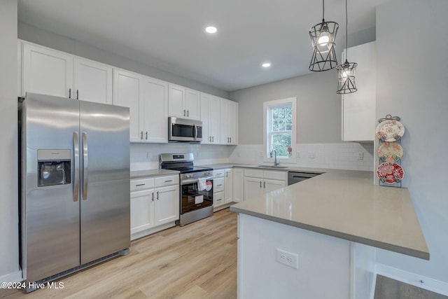 kitchen with backsplash, white cabinets, appliances with stainless steel finishes, decorative light fixtures, and kitchen peninsula