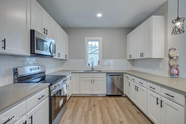 kitchen featuring decorative light fixtures, white cabinetry, sink, and appliances with stainless steel finishes