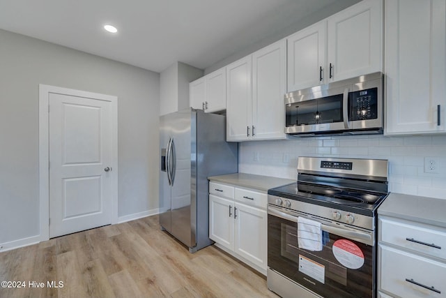 kitchen featuring white cabinets, appliances with stainless steel finishes, light wood-type flooring, and decorative backsplash