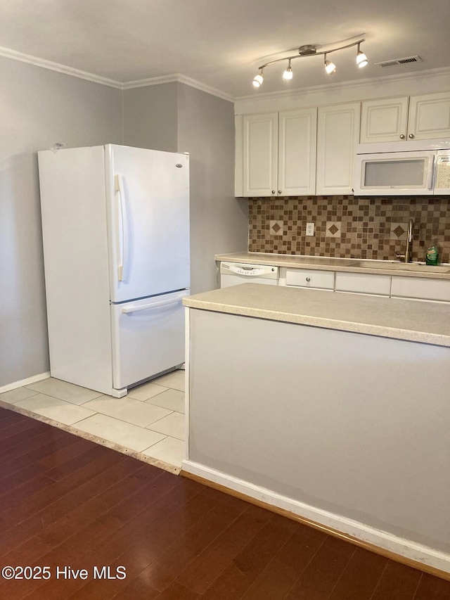 kitchen with tasteful backsplash, light tile patterned flooring, crown molding, white appliances, and white cabinetry