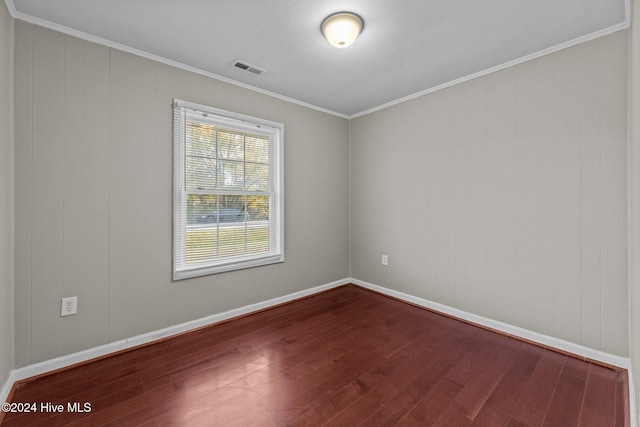 spare room featuring wood-type flooring and crown molding