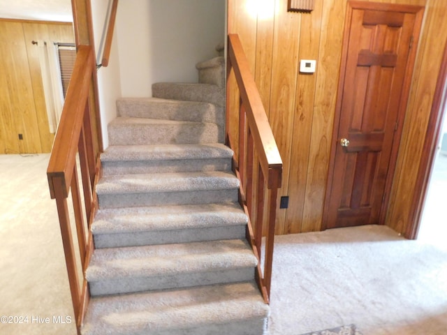 staircase featuring carpet flooring and wooden walls