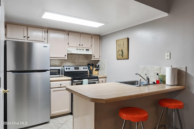 kitchen with kitchen peninsula, appliances with stainless steel finishes, backsplash, a breakfast bar, and sink