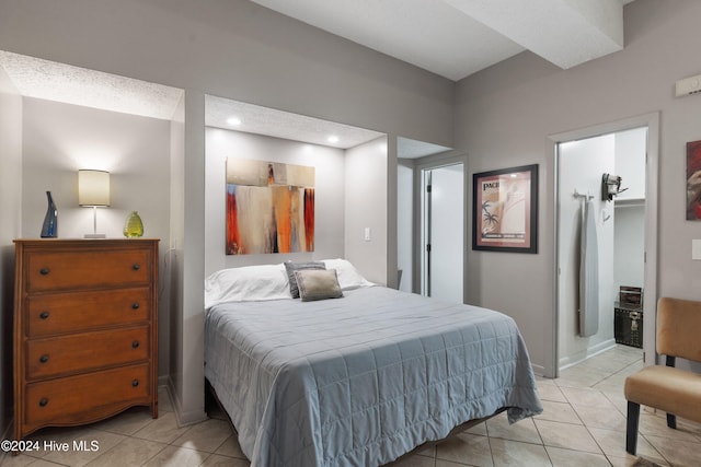 bedroom with a spacious closet, light tile patterned floors, and a textured ceiling