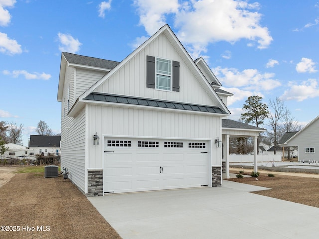 view of front of home featuring an attached garage, stone siding, concrete driveway, and a standing seam roof