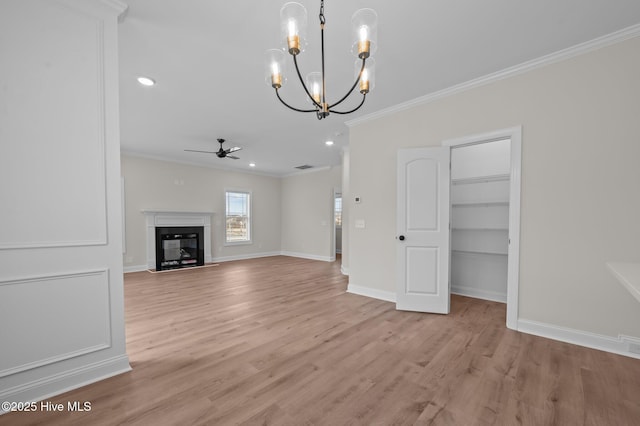 unfurnished living room with light wood-type flooring, a glass covered fireplace, crown molding, and baseboards