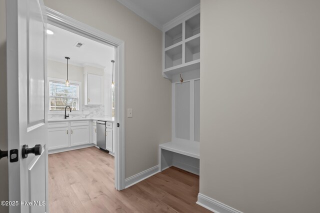 mudroom featuring crown molding, visible vents, light wood-style flooring, a sink, and baseboards