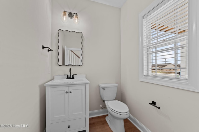 half bathroom featuring wood finished floors, vanity, toilet, and baseboards