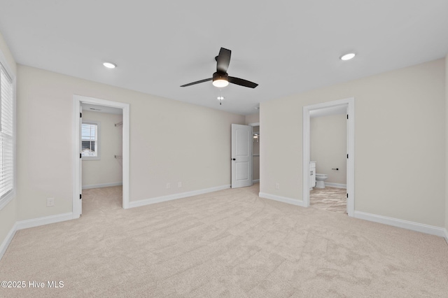 unfurnished bedroom featuring a walk in closet, recessed lighting, light colored carpet, ensuite bathroom, and baseboards