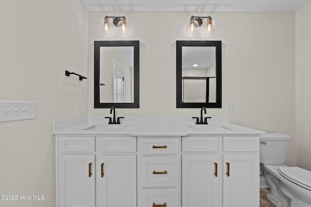 bathroom featuring toilet, double vanity, a sink, and a shower with shower door