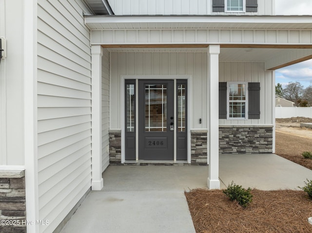 doorway to property featuring stone siding and a porch