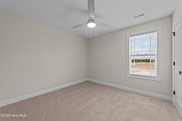 empty room featuring light carpet, ceiling fan, visible vents, and baseboards