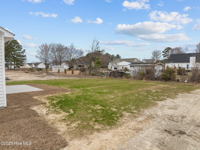 view of yard featuring an outbuilding, a storage shed, and a residential view