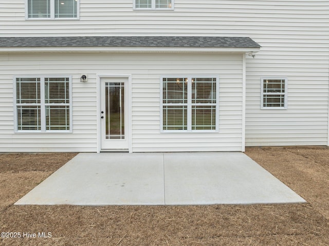 property entrance featuring a patio and roof with shingles