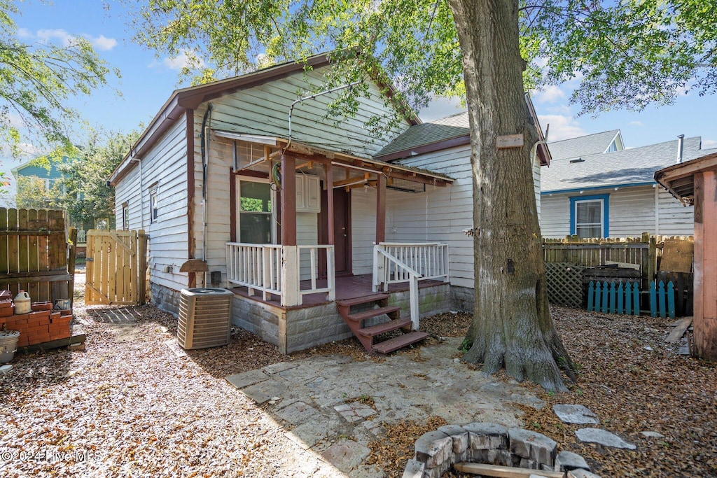 bungalow-style house with cooling unit, a deck, and a fire pit