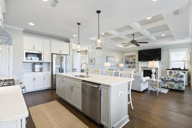 kitchen featuring white cabinets, appliances with stainless steel finishes, a center island with sink, and sink