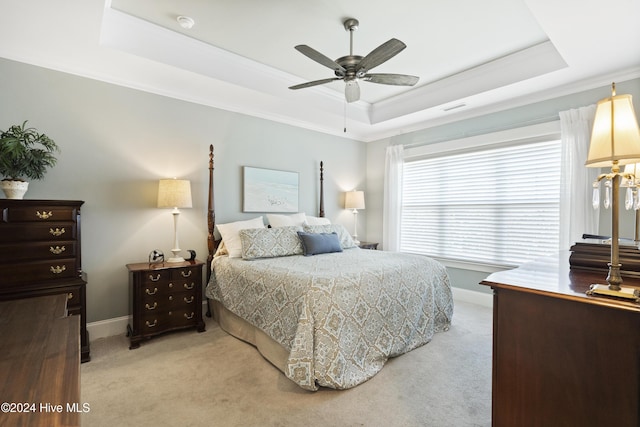 carpeted bedroom featuring a tray ceiling, ceiling fan, and crown molding