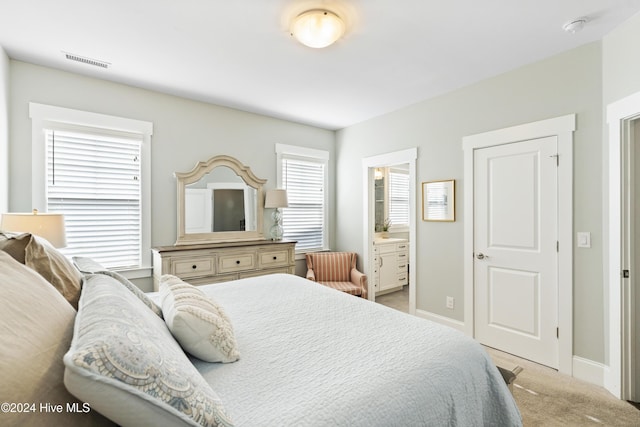 bedroom with light colored carpet and ensuite bath