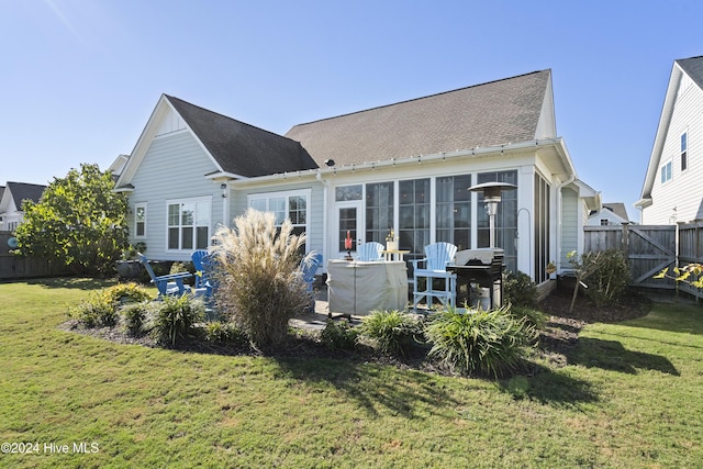 back of house with a sunroom and a lawn