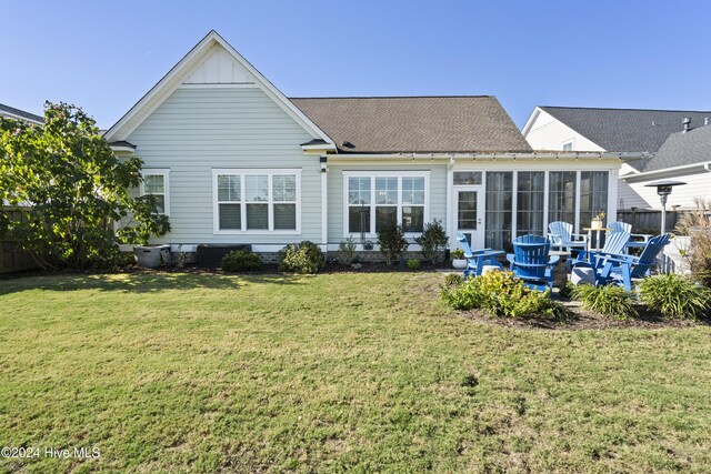 rear view of property featuring a sunroom and a yard