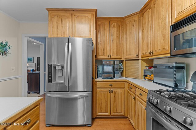 kitchen featuring crown molding, stainless steel appliances, and light hardwood / wood-style floors