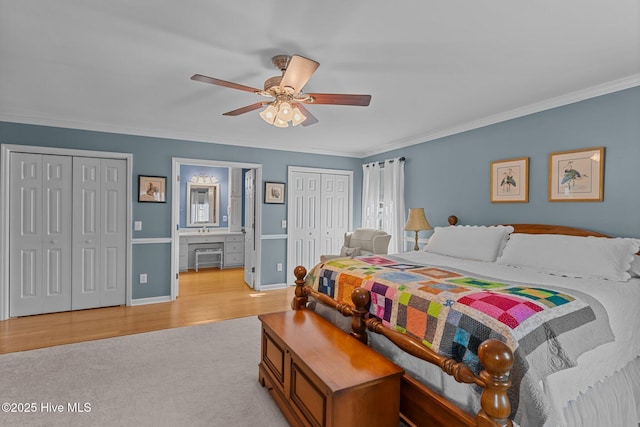 bedroom featuring multiple closets, crown molding, ensuite bathroom, and ceiling fan