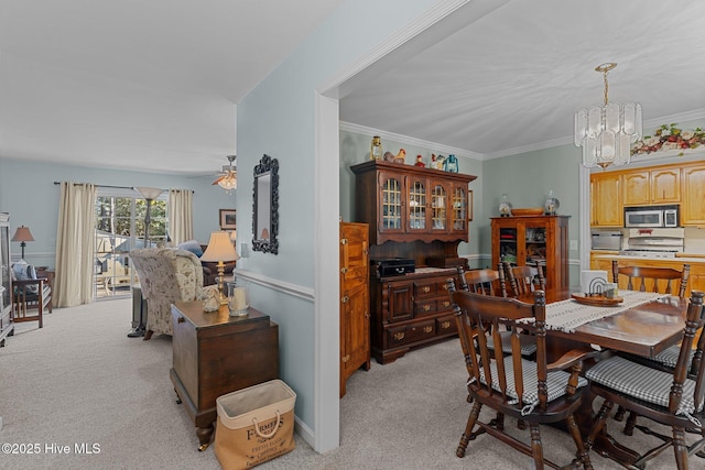 carpeted dining space with ornamental molding and ceiling fan with notable chandelier