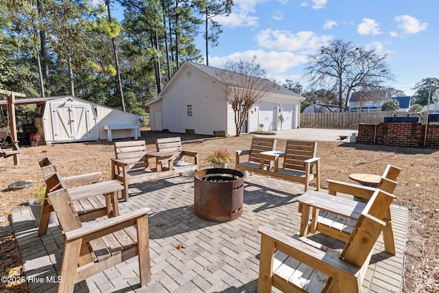 view of patio / terrace with a storage unit, an outdoor fire pit, and a garage