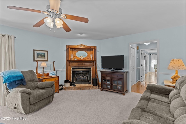 living room with ceiling fan, light colored carpet, and a fireplace