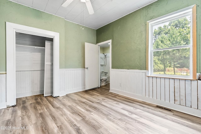 401 Pecan Ln, Lake Waccamaw, NC 28450 - unfurnished bedroom with multiple windows, wood finished floors, ceiling fan, a closet, and a wainscoted wall
