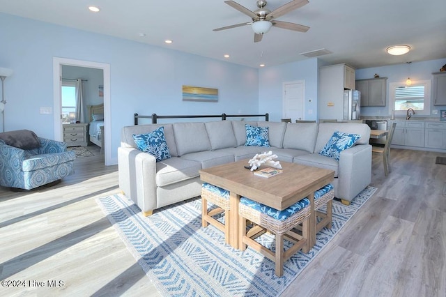 living room with ceiling fan, light hardwood / wood-style flooring, a healthy amount of sunlight, and sink