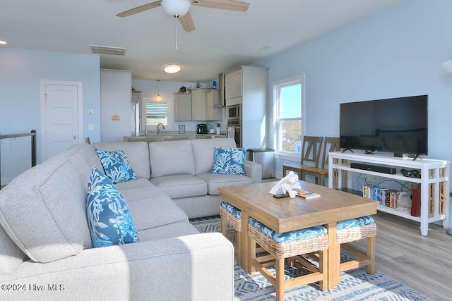 living room featuring light hardwood / wood-style floors, ceiling fan, and sink