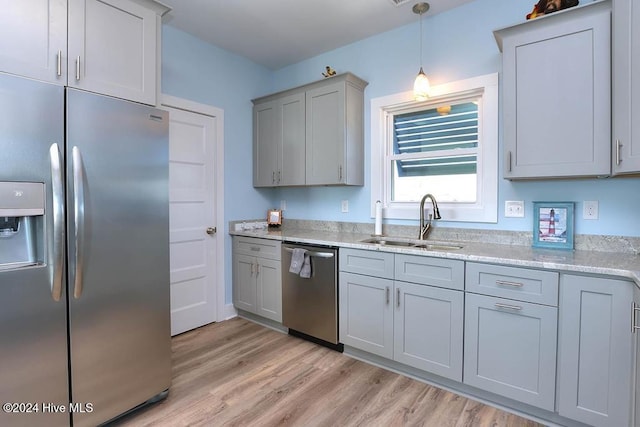 kitchen featuring light stone countertops, appliances with stainless steel finishes, sink, gray cabinets, and light hardwood / wood-style floors