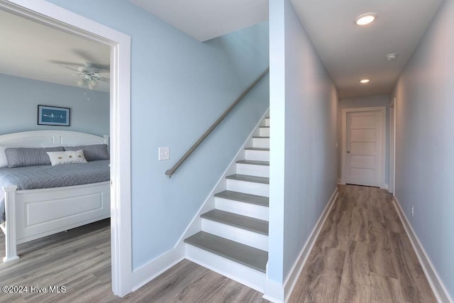 staircase with hardwood / wood-style floors and ceiling fan