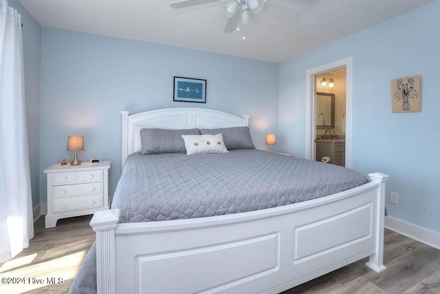 bedroom featuring hardwood / wood-style floors, ensuite bathroom, ceiling fan, and sink