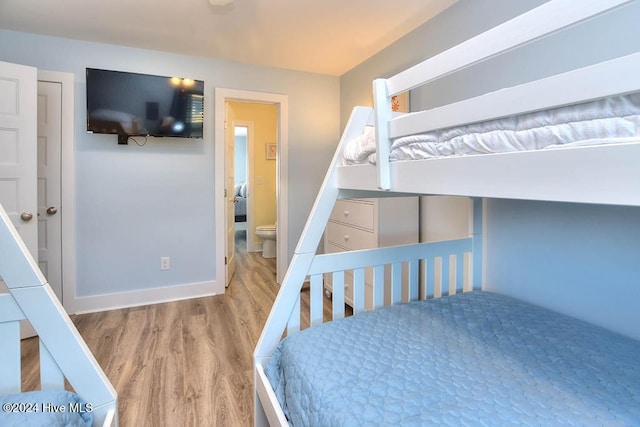 bedroom with connected bathroom and light hardwood / wood-style flooring